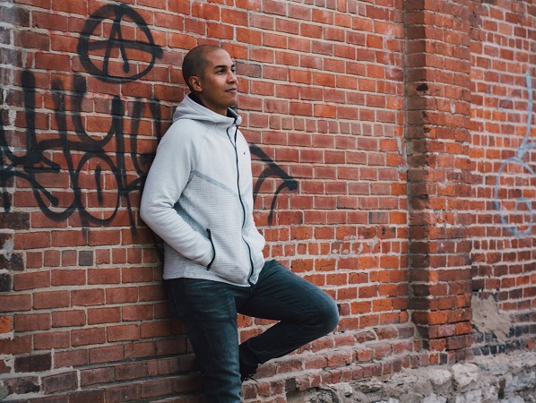 david delaine leaning against brick wall with graffiti