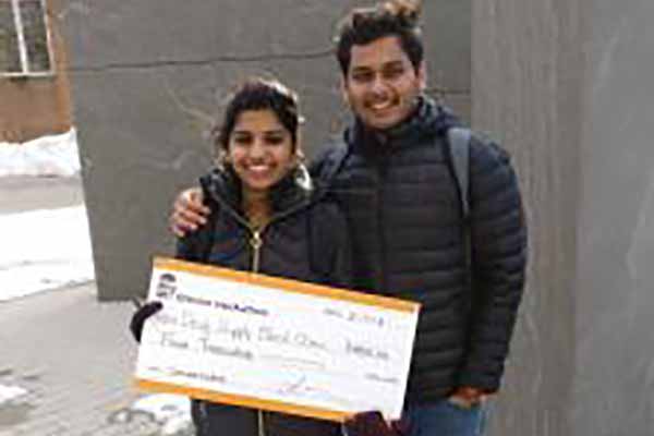 two people holding a blown up sign that models a check