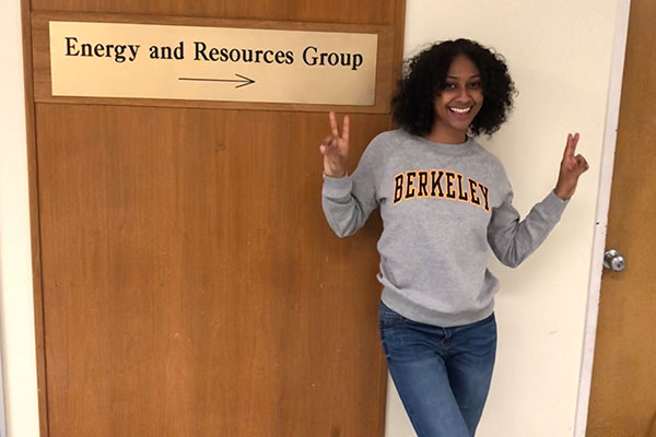 student with Berkeley sweatshirt standing in front of Energy and Resources group sign on door