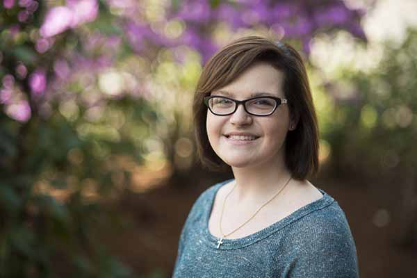 female student posing with a smile with landscape in the background