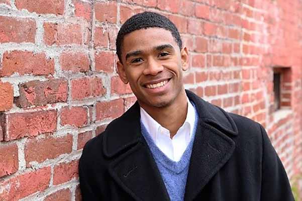 student smiling with brick wall in background