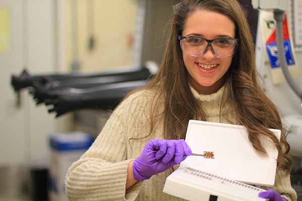 student in lab with safety glasses holding device