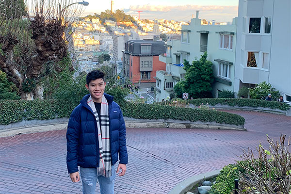 student poses while in Hong Kong with city in background