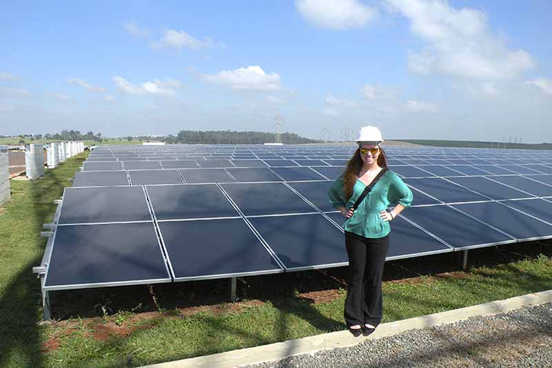 student in hard hat with rows of solar panels in background