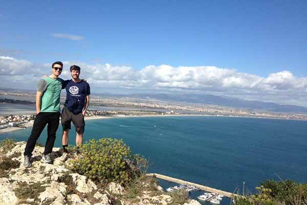 two students on cliff overlooking body of water