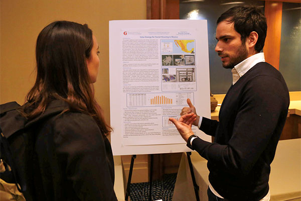 Ricardo Careaga speaking to a student in front of his research poster