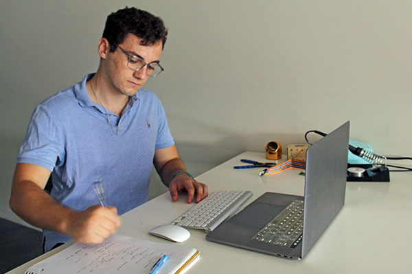 student on co-op working at desk with laptop and writing