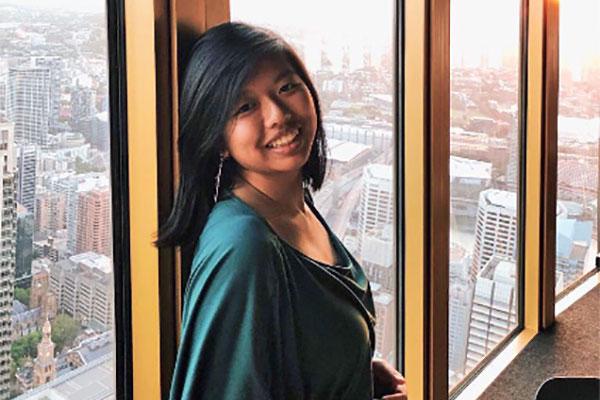 student posing with Boston skyline in background