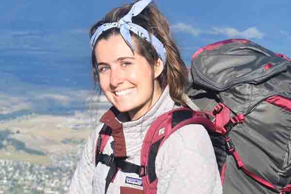 student on hike with backpack on top of mountain