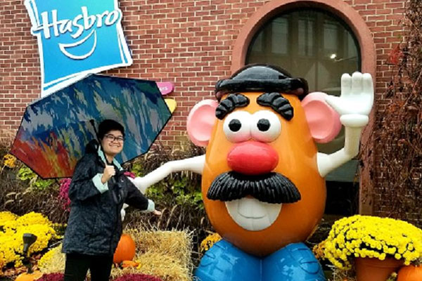 student on co-op posing with Mr. Potato Head at Hasbro