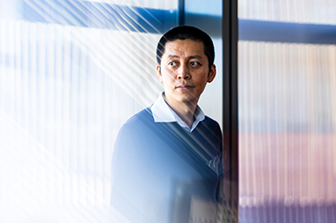 Jing-Ke Weng standing in front of a window looking off to the left