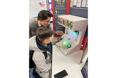 Jose Meza LIamosas standing next to a child as they play the candy game he engineered