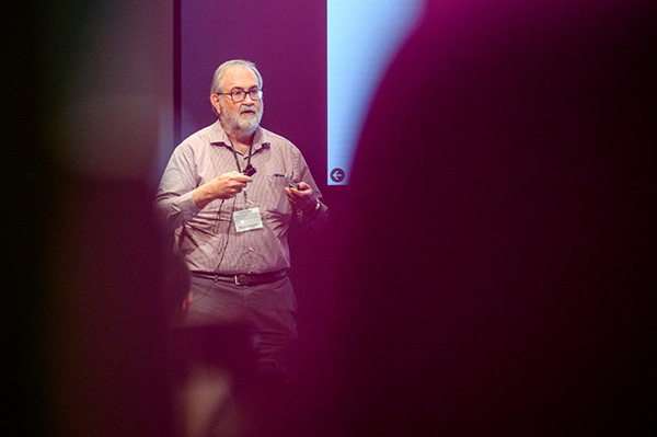 Herbert Levine, distinguished professor of physics and bioengineering, standing in front of a project giving a presentation