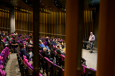 Herbert Levine, distinguished professor of physics and bioengineering, standing in front of a project giving a presentation in the front of a lecture hall
