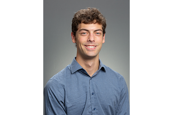 Joshua Piatok, E’25, bioengineering, headshot. He is wearing a blue dress shirt and the background is grey.