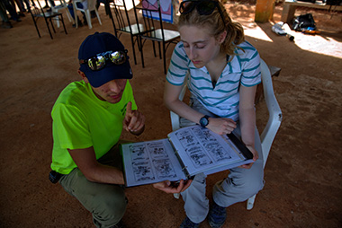 Jose Meza LIamosas looking at a book crouching next to a women