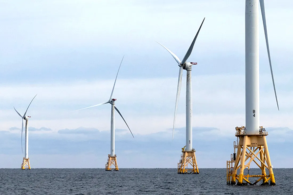 four offshore wind turbines on a cloudy but clear day