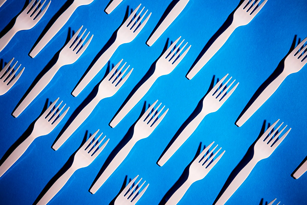 plastic forks evenly distributed on blue background