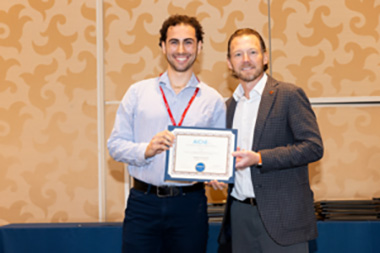 Dominic Pizzarella, chemical engineering student, holding his AIChE award standing next to a man.