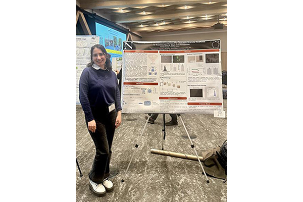 student standing in front of research poster