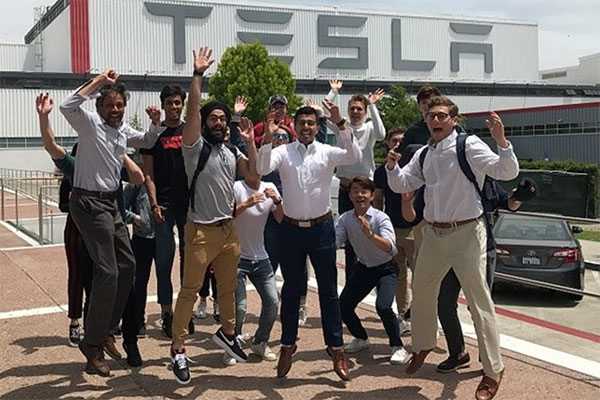 Students jumping in front of Tesla building