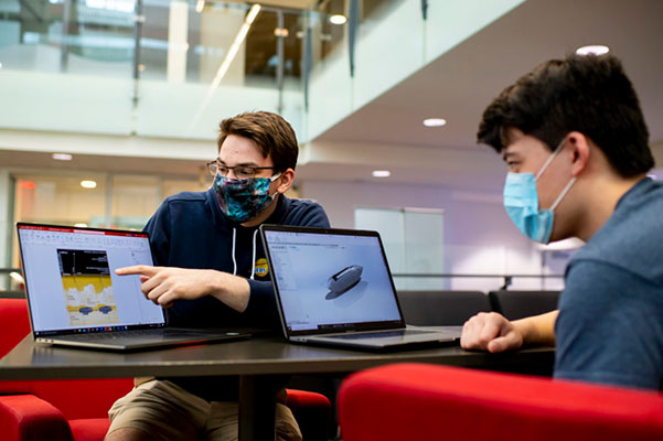 two students working on competition project on laptops
