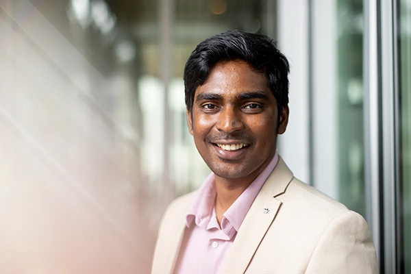 Aravind Nagulu, a professor of electrical and computer science, smiling for a headshot. wearing a white blazer and pink button up shirt