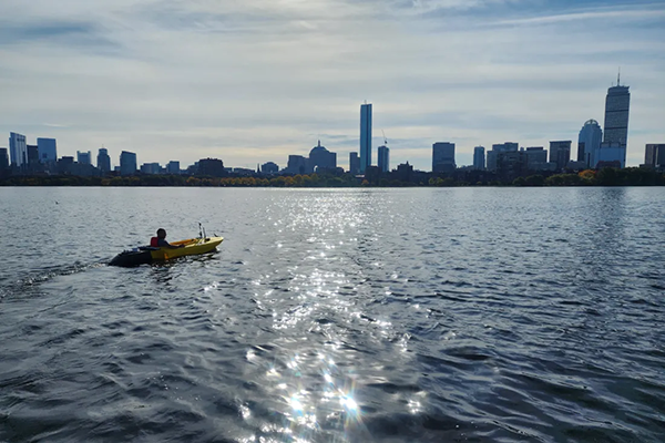a person in a kayak on the charles river with the boston cityscape in the back