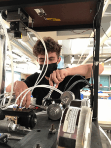 student with a wrench working on an engine
