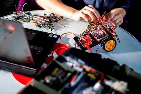 student hands working on robotics project of model motorized vehicle