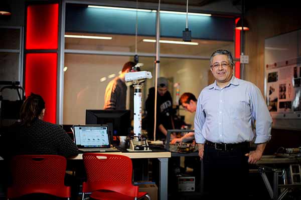 professor in foreground with robotics lab blurred in background